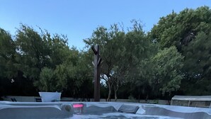 Een hottub met rood licht in het water, omringd door bomen.