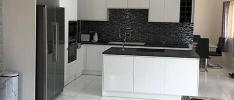A modern kitchen with white cabinetry, a black backsplash, and a central island.