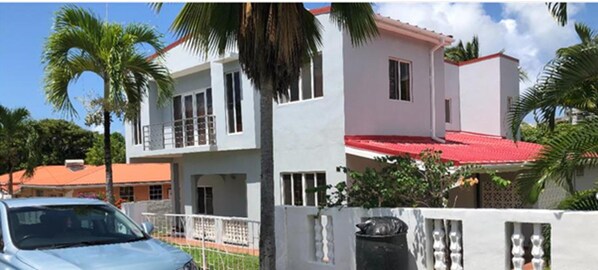 A two-story house with a red roof, white walls, and a balcony. - Stunning 3-bed Apartment in Rodney Bay (Gros Islet)