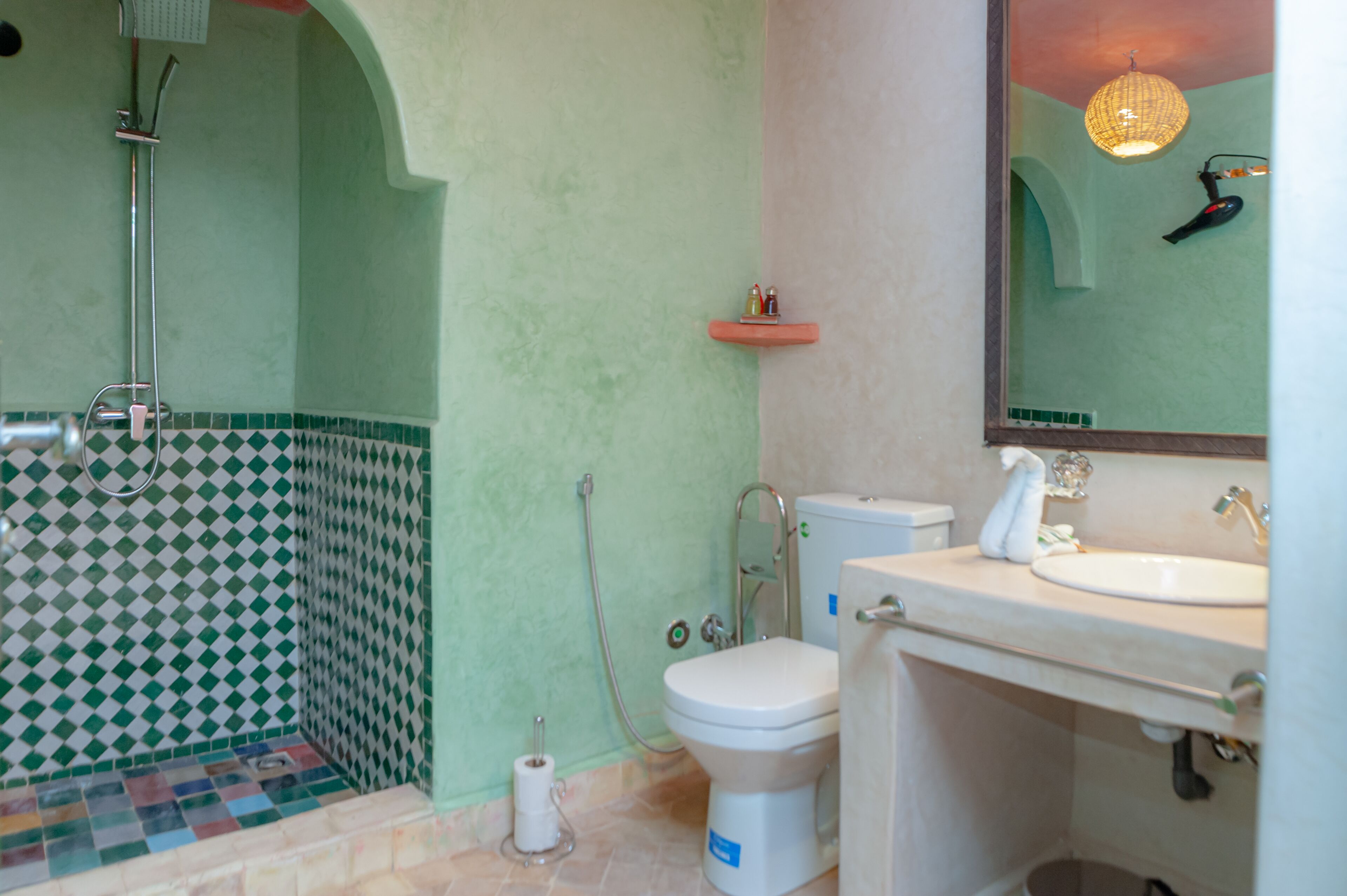 A bathroom with a shower, toilet, sink, and a mirror.