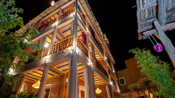Un edificio de varios pisos con balcones, barandillas de madera y luces colgantes.