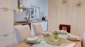 Une cuisine moderne avec des meubles blancs, une table à manger dressée avec des assiettes, des verres et un centre de table.