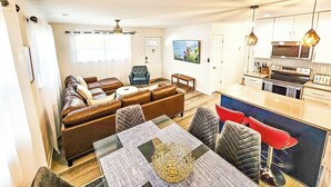 Ein modernes Wohnzimmer mit einer braunen Ledersofa, einem Esstisch mit Stühlen und einer Küchenzeile inklusive Mikrowelle und Herd.