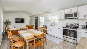 A modern kitchen with white cabinets, stainless steel appliances, and a wooden dining table with chairs.