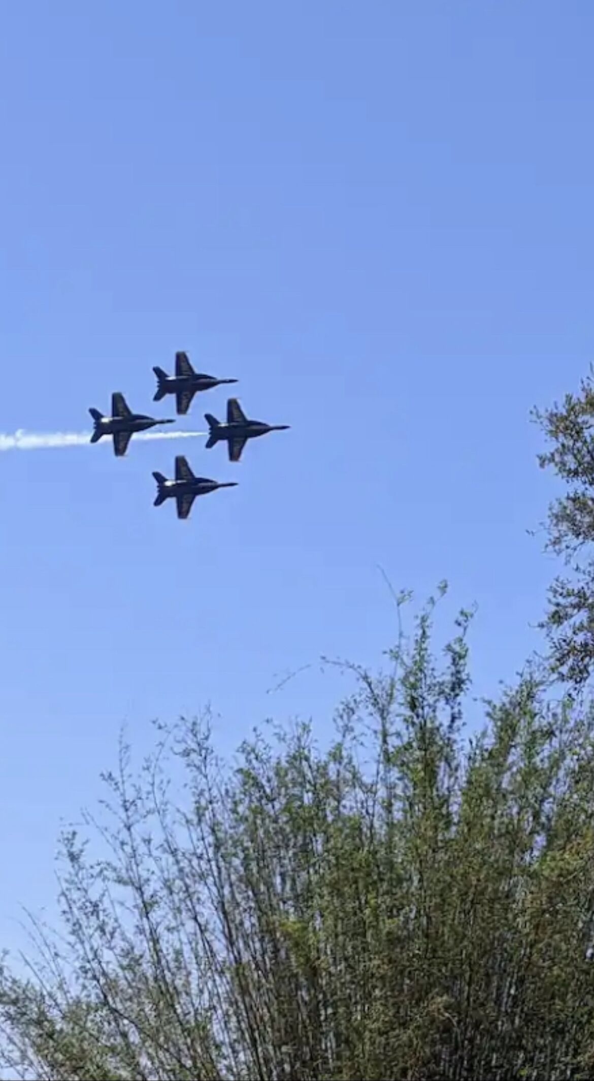 Four jets flying in formation against a clear blue sky.