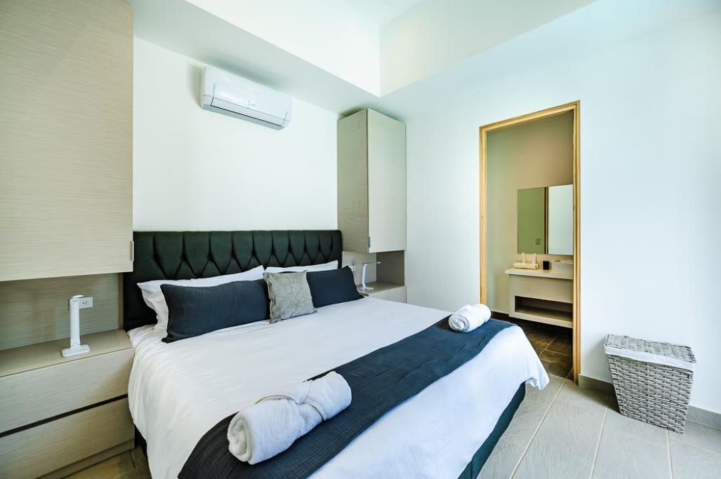 A modern hotel room with a neatly made bed, a large mirror, and a small trash bin.