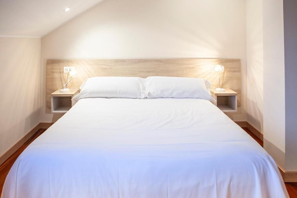 Une chambre avec un grand lit, deux tables de chevet avec des lampes et un plafond en pente.