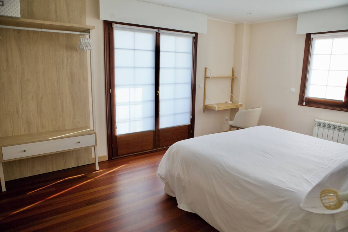 Une chambre à coucher avec un lit, une armoire en bois, un bureau, une chaise et une fenêtre.
