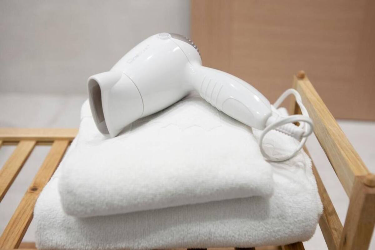 Une serviette blanche et un sèche-cheveux blanc sont posés sur une chaise en bois.