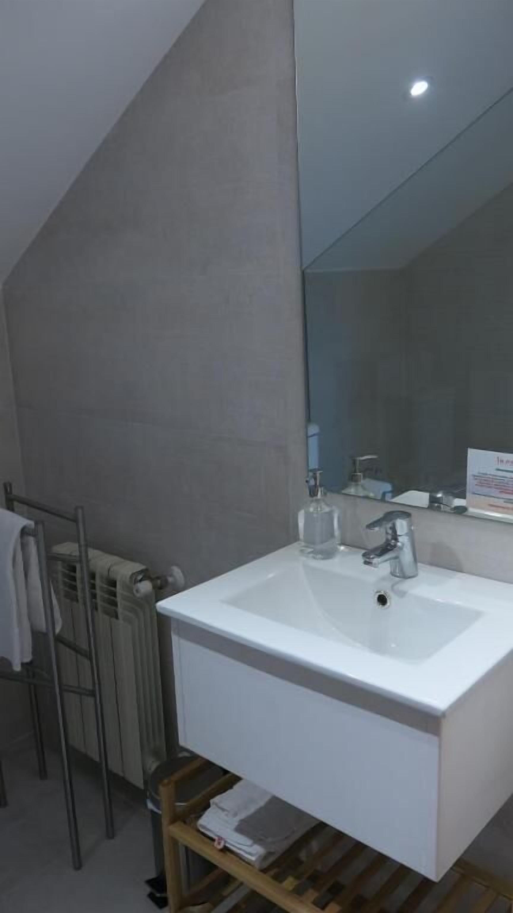 A modern bathroom with a white sink, a mirror, and a towel rack.