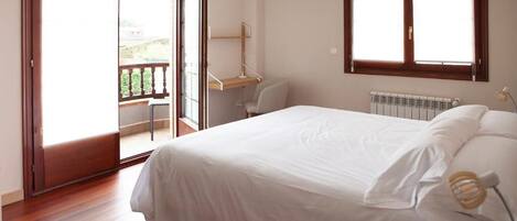 A bedroom with a bed, a desk, and a chair. There is a sliding door leading to an outdoor area.