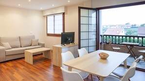 A modern living room with a sofa, coffee table, TV, and dining area with chairs and a table.