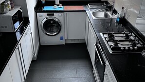 Une cuisine de taille réduite équipée d’un lave-linge, d’une cuisinière et d’un évier.