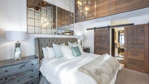 A bedroom with a large bed, a dresser, a mirror, and a sliding barn door.