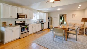 A modern kitchen with white cabinets, stainless steel appliances, and a dining area with a table and chairs. - Gorgeous country cottage (Springfield)