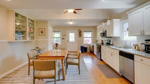 A modern kitchen with wooden cabinets, a dining table with chairs, and a ceiling fan. - Gorgeous country cottage (Springfield)