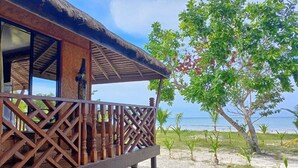 Une terrasse en bois, surmontée d’un toit de chaume, qui offre une vue sur la plage.