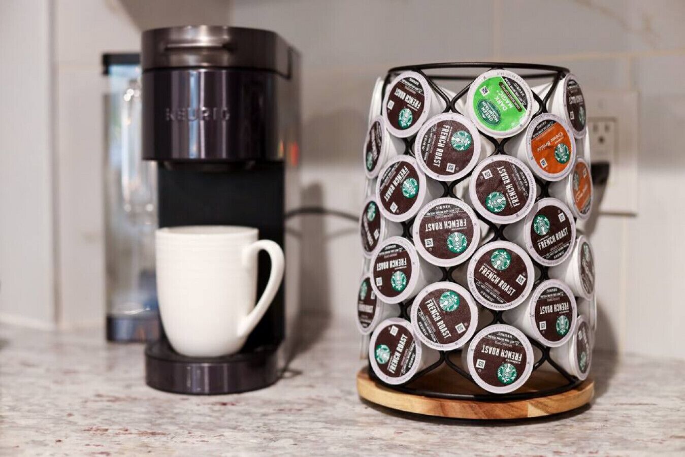 A coffee maker and a mug filled with coffee capsules.