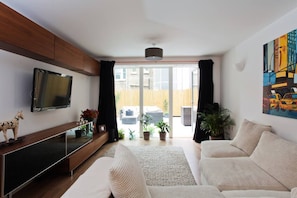 Ein modernes Wohnzimmer mit einer Couch, einem Fernseher und einem großen Fenster.