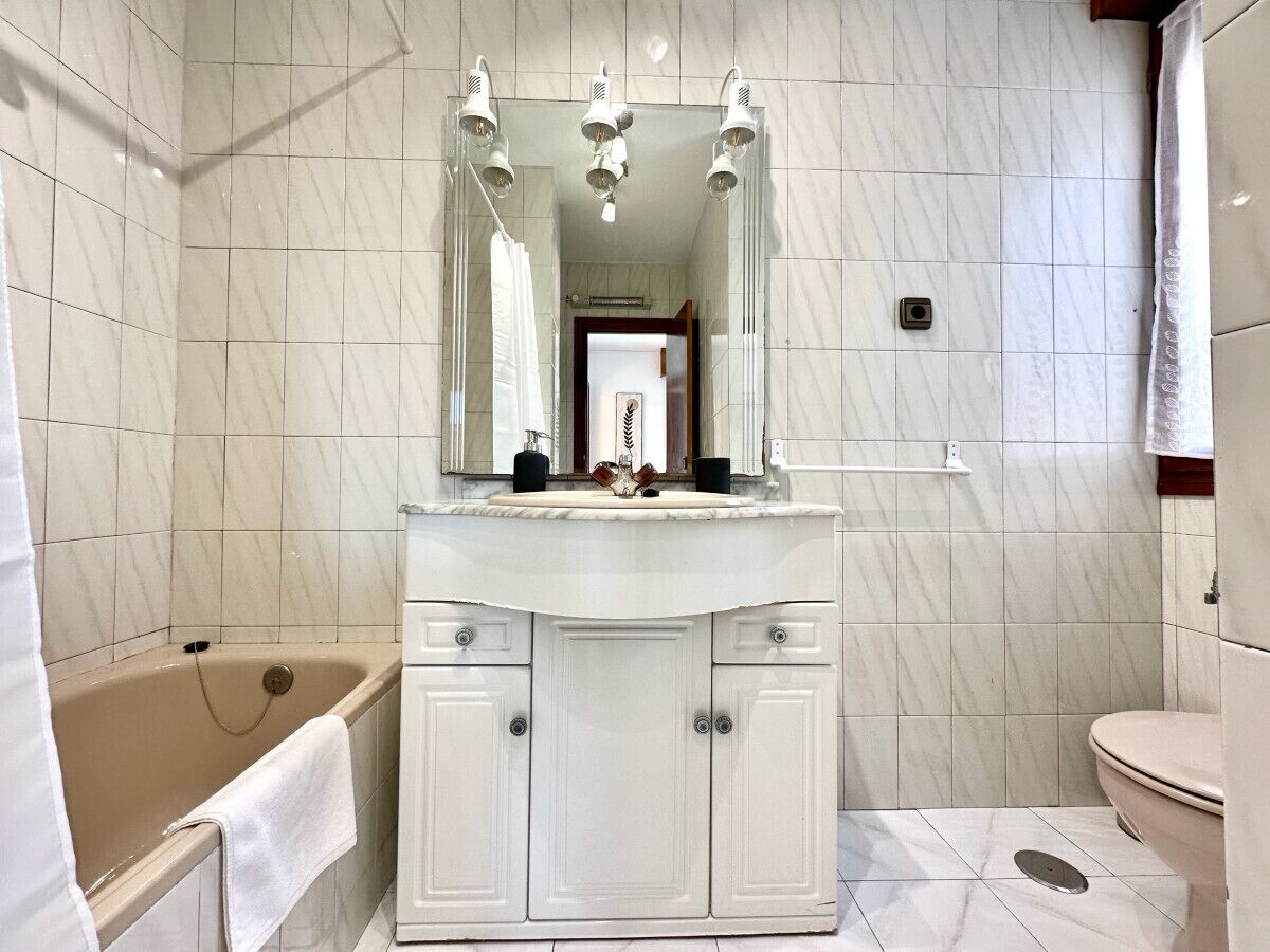 A bathroom with a bathtub, a toilet, a sink with a mirror, and a shower curtain.