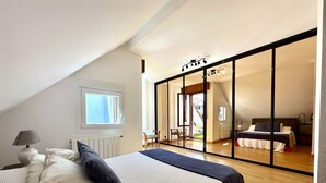 A bedroom with a large bed, a window, a radiator, and a sliding glass door leading to another room.