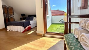 A bedroom with a bed, a small table, and a view of a green lawn through a glass door.