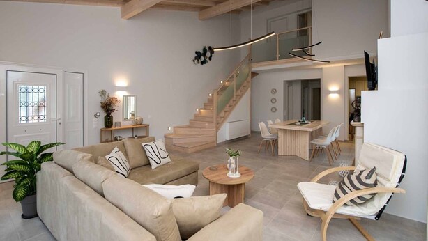 Ett modernt vardagsrum med en soffa, en gungstol, en matplats och en trappa.