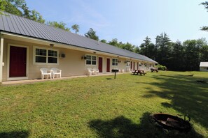 A motel with a single-story structure, a red door, and a covered parking area. - The Villager Motel (Bartlett)