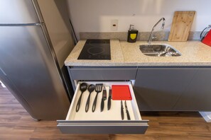 A kitchen with a stainless steel refrigerator, a granite countertop, a sink, and a drawer with utensils. - Arte Arquitetura Vila Mariana (São Paulo)