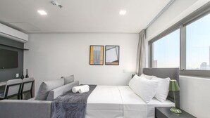 Une chambre d  ’hôtel moderne, équipée d’un lit, d’un bureau et d’une grande fenêtre.