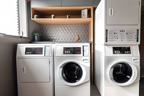 A compact laundry area with two front-loading washing machines and a small shelf with decorative items. - Arte Arquitetura Vila Mariana (São Paulo)