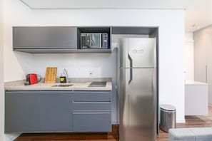 A compact kitchen with a built-in microwave, a stainless steel refrigerator, and grey cabinetry. - Arte Arquitetura Vila Mariana (São Paulo)