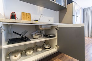 A kitchen with a sink, a stove, and various pots and pans stored on shelves. - Arte Arquitetura Vila Mariana (São Paulo)