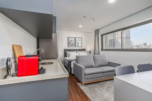 A modern apartment with a kitchen, dining area, and a bed.