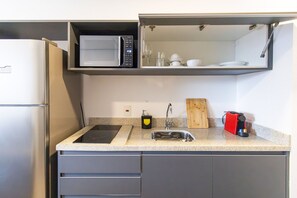 A compact kitchen with a built-in microwave, a sink, and a cutting board. - Arte Arquitetura Vila Mariana (São Paulo)