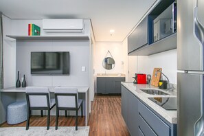 A modern kitchen with a built-in TV, grey cabinets, and a wooden floor. - Arte Arquitetura Vila Mariana (São Paulo)