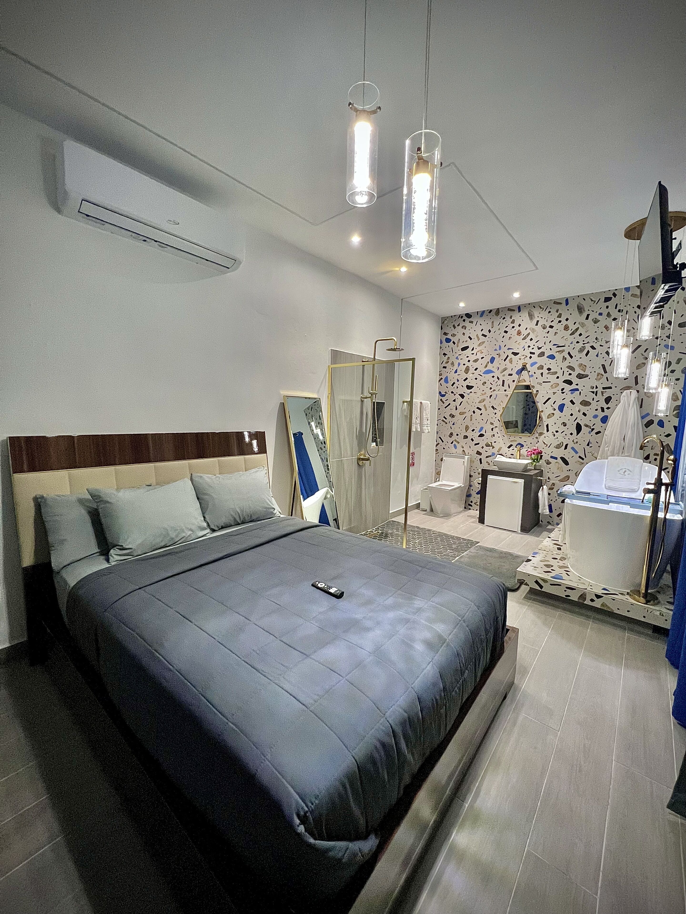 Una camera d'albergo moderna con un letto grande, una zona doccia e un bagno con vasca.