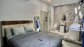 Una camera d'albergo moderna con un letto grande, una zona doccia e un bagno con vasca.