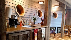Una cocina rústica con gabinetes de madera, una cafetera y un lavamanos.
