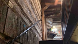 Una escalera de madera con barandilla que lleva a una habitación con ventilador de techo y ventana.