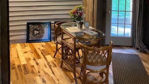Un comedor con suelo de madera, una mesa de vidrio y sillas de mimbre.
