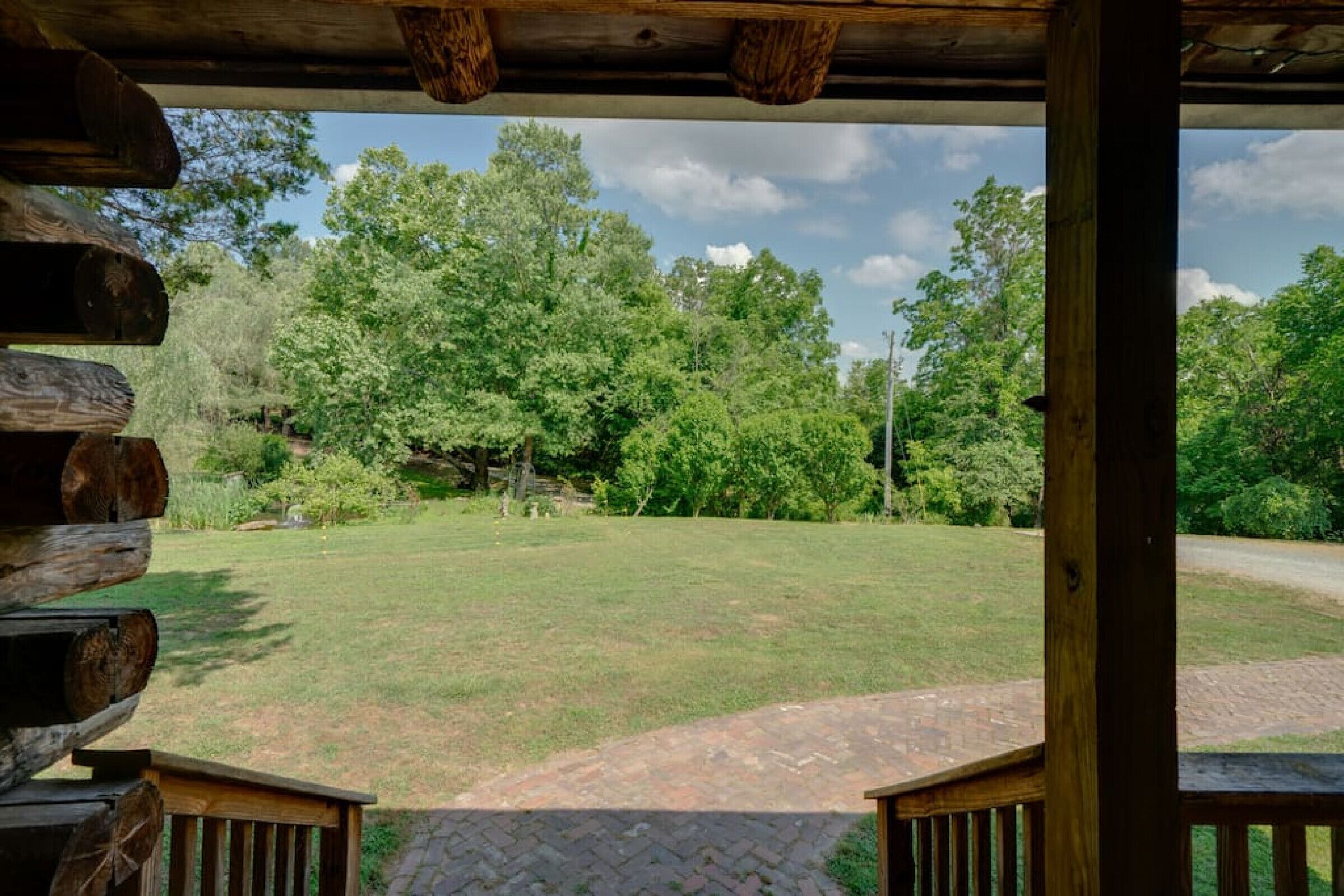 A wooden deck with a view of a grassy yard and trees.