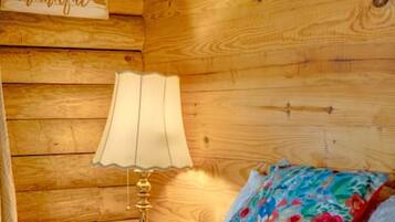 A wooden cabin interior with a bed, a lamp, and a 'thankful' sign on the wall.