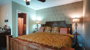 Une chambre à coucher avec un lit en bois, un papier peint à motifs, deux lampes de chevet et un ventilateur de plafond.