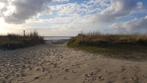 A sandy beach path leading to the ocean, with footprints and tall grasses on either side. - Beautiful, bright vacation apartment with swimming pool, Residence Kormoran15 (Cuxhaven)