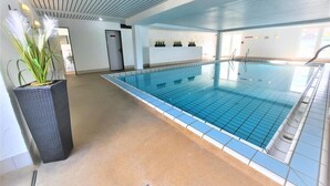 An indoor swimming pool with a tiled floor and a ceiling with horizontal lines. - Beautiful, bright vacation apartment with swimming pool, Residence Kormoran15 (Cuxhaven)