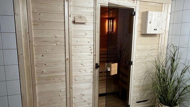 A wooden wardrobe with a mirrored door, a small cabinet above it, and a potted plant beside the wardrobe. - Beautiful, bright vacation apartment with swimming pool, Residence Kormoran15 (Cuxhaven)
