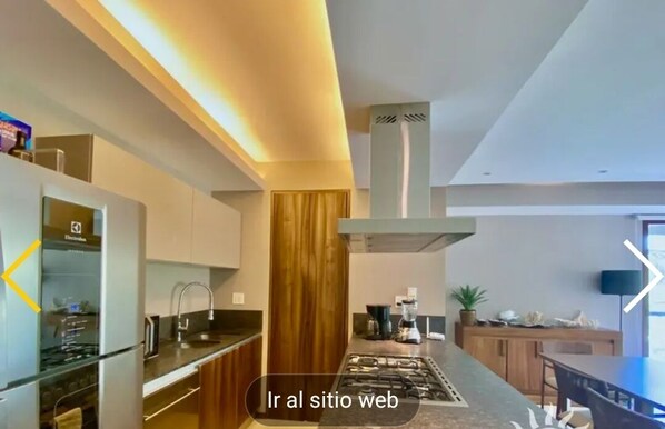 A modern kitchen with a central island, built-in appliances, and a wooden accent wall.