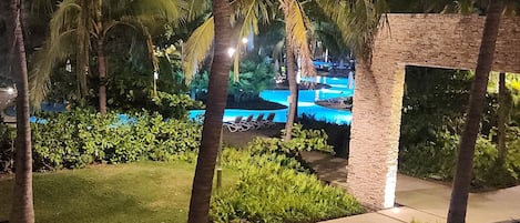 Nattebillede af et resortområde med palmer, en swimmingpool og en bygning i mursten.