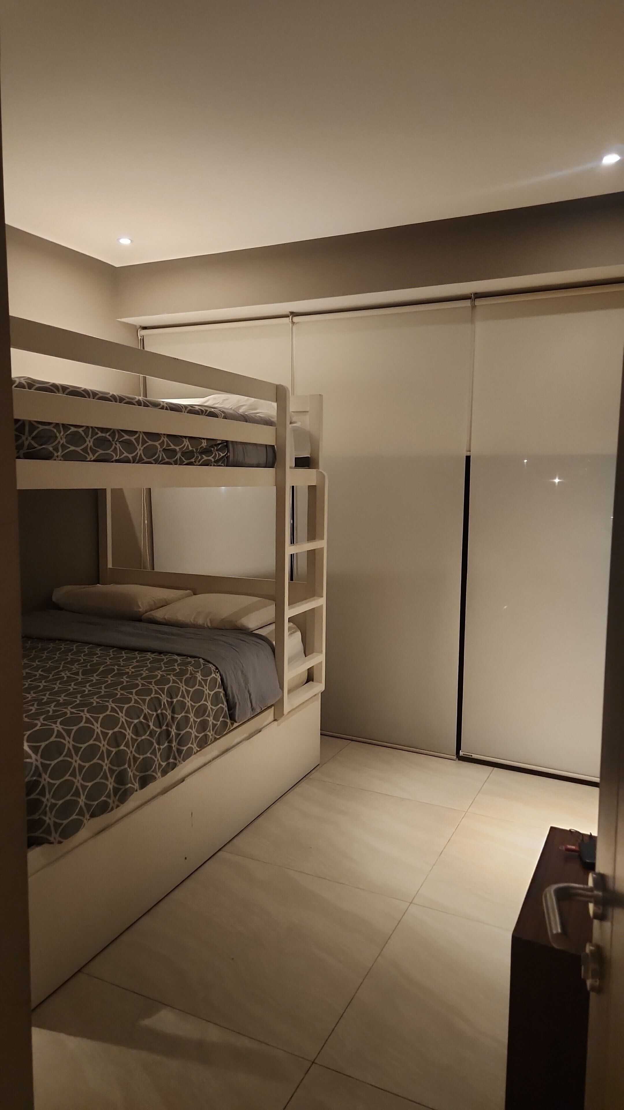 Une chambre avec un lit superposé, une armoire et une porte.